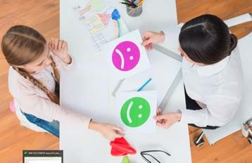 image représentant deux enfants autour d'une table avec des feuille contenant des smiley : un vert satisfait et un violet insatisfait